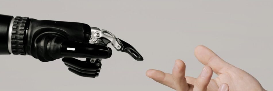 A human hand reaching to touch a bionic prosthetic hand on a white background.
