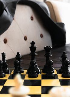 Close-up of chess pieces on a yellow board, highlighting strategy and focus.