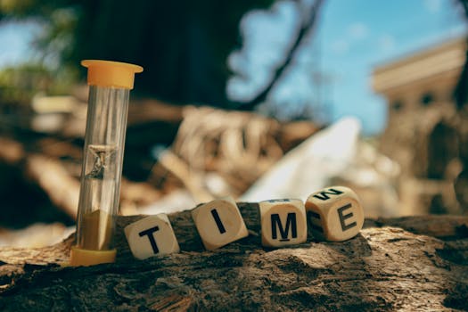 Hourglass and wooden blocks with letters spelling 'TIME' on a sunny day outdoors.