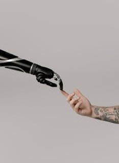 Close-up of a prosthetic arm and a human hand reaching towards each other in harmony.