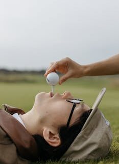 Unique concept photo of a person lying on grass with a golf tee and ball in mouth, showcasing sport and creativity.